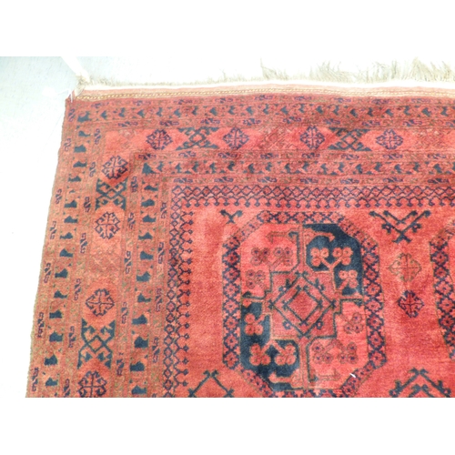 45 - An Afghan rug, decorated with hexagonal guls, stylised designs and a border, on a red ground  64