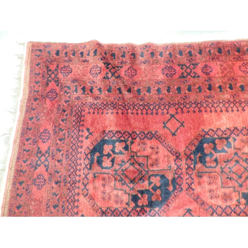 45 - An Afghan rug, decorated with hexagonal guls, stylised designs and a border, on a red ground  64