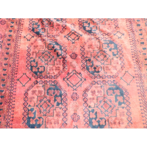 45 - An Afghan rug, decorated with hexagonal guls, stylised designs and a border, on a red ground  64