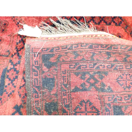 45 - An Afghan rug, decorated with hexagonal guls, stylised designs and a border, on a red ground  64