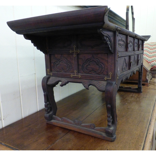 58 - A 20thC Korean style fruitwood table top, altar style, three drawer cabinet, raised on carved feet  ... 