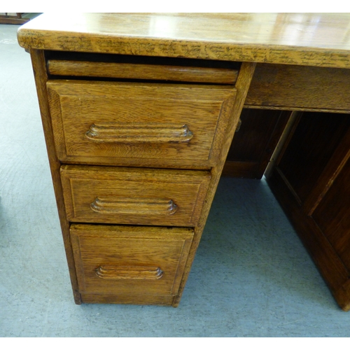 A late 19th/early 20thC oak twin pedestal seven drawer desk, on a ...