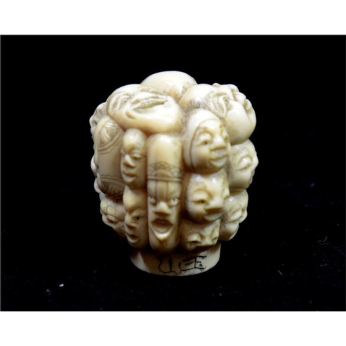 108 - λ A Japanese carved ivory pommel, Meiji, 19th century, carved with heads, signed, 4.5cm long