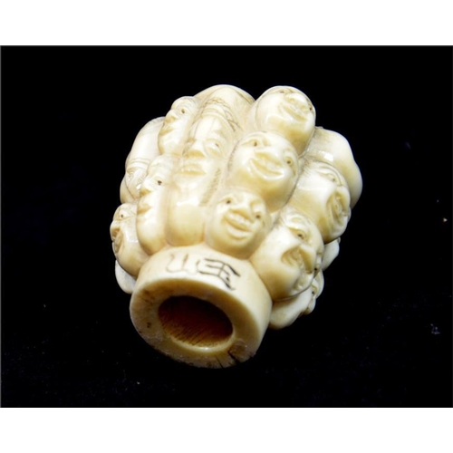 108 - λ A Japanese carved ivory pommel, Meiji, 19th century, carved with heads, signed, 4.5cm long