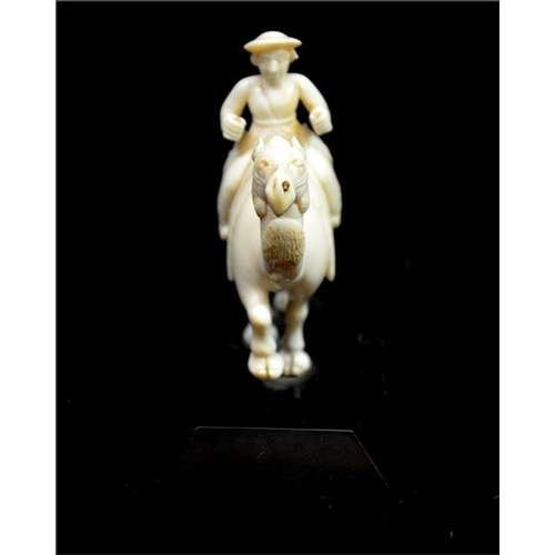 110 - λ An Oriental carved ivory figure of a man on camel, 19th century, Anglo Indian, on black marble bas... 