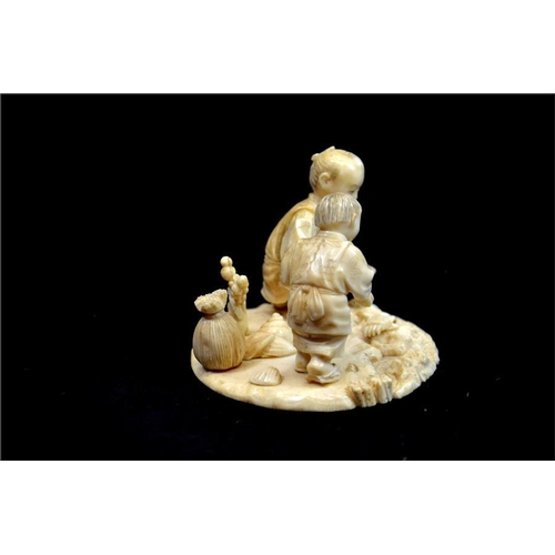 120 - λ A Japanese carved ivory okimono, Meiji, 19th century, modelled as a father and son cockle picking ... 