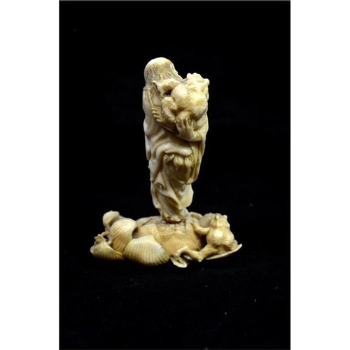 122 - λ A Japanese carved ivory okimono, Meiji, 19th century, modelled as a grotesque sage with toads, sta... 