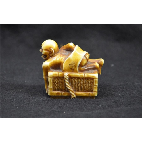 125 - λ A Japanese carved ivory netsuke, Meiji, 19th century, modelled as an emaciated figure on a box, st... 