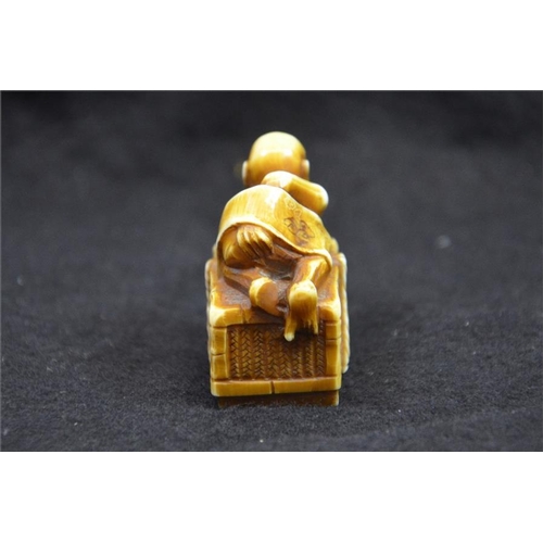 125 - λ A Japanese carved ivory netsuke, Meiji, 19th century, modelled as an emaciated figure on a box, st... 