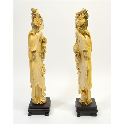 129 - A pair of Chinese carved ivory figures, 19th century, modelled as women holding lotus flowers, on st... 