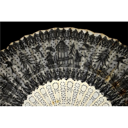 175 - A 19th century lace fan, with a black lace leaf decorated with figures, parrots, trees and buildings... 