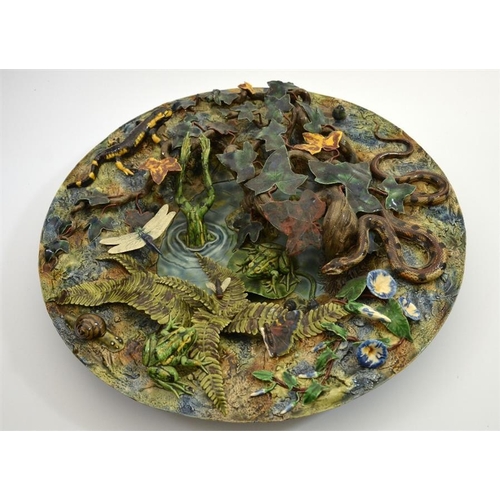 1592 - A large Palissy ware charger, modelled in high relief as a woodland pond with frogs, insects and rep... 