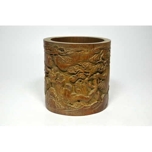 39 - A Chinese bamboo brush pot, cylindrically formed and carved with figures in a wooded landscape, and ... 