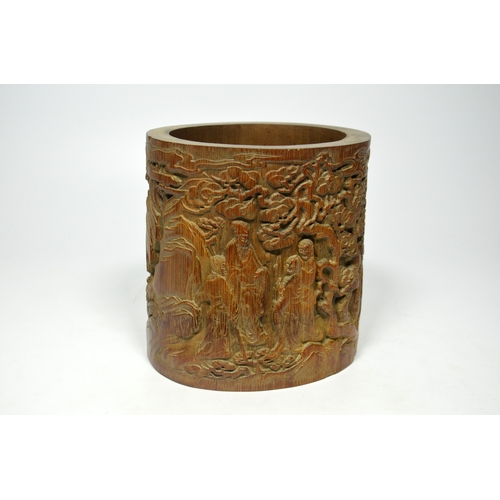 39 - A Chinese bamboo brush pot, cylindrically formed and carved with figures in a wooded landscape, and ... 