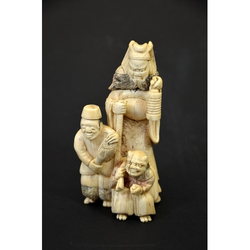 29 - λ A 19th century Japanese carved ivory okimono, modelled as three grotesque figures, holding lantern... 