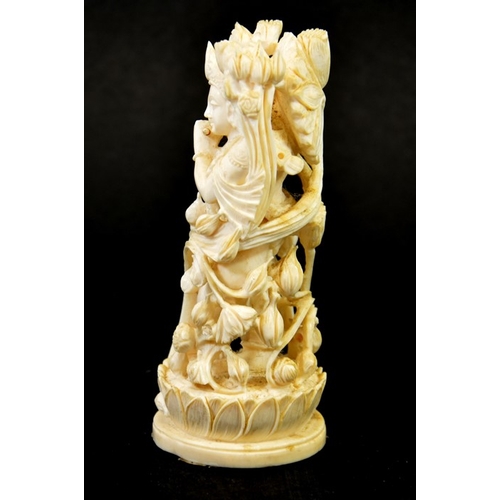 32 - λ A 19th century Indian carved ivory figure of a deity playing the pipe, within a floral cage, stand... 