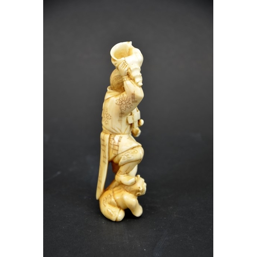 33 - λ A 19th century Japanese carved ivory okimono, Meiji, modelled as a Samurai holding a conch shell, ... 