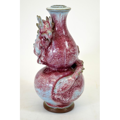 9 - A Chinese double gourd vase, sang de boeuf with relief moulded dragon, entwined, 24cm high