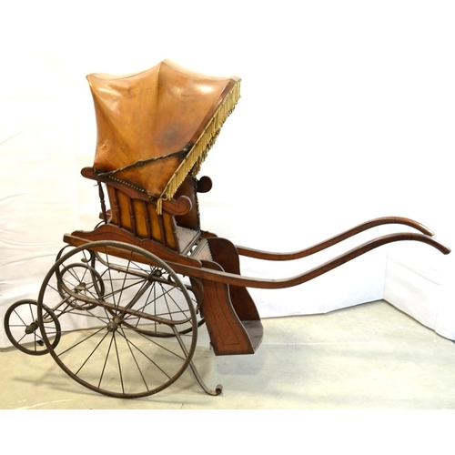 120 - A Victorian wooden pram with brown leather studded hood and interior, on two large wheels with two s... 