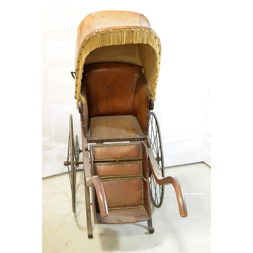 120 - A Victorian wooden pram with brown leather studded hood and interior, on two large wheels with two s... 