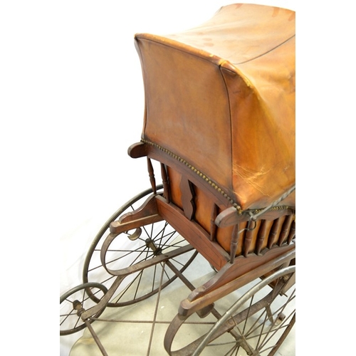 120 - A Victorian wooden pram with brown leather studded hood and interior, on two large wheels with two s... 