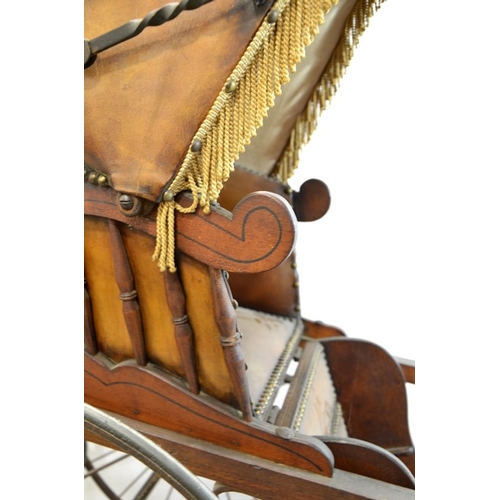 120 - A Victorian wooden pram with brown leather studded hood and interior, on two large wheels with two s... 