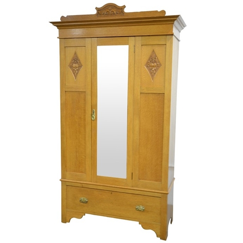 148 - An Arts and Crafts light oak wardrobe, three panel with single mirrored door, flanked by carved loze... 