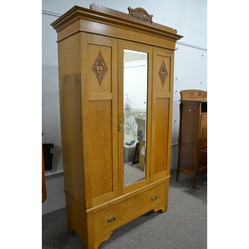 148 - An Arts and Crafts light oak wardrobe, three panel with single mirrored door, flanked by carved loze... 