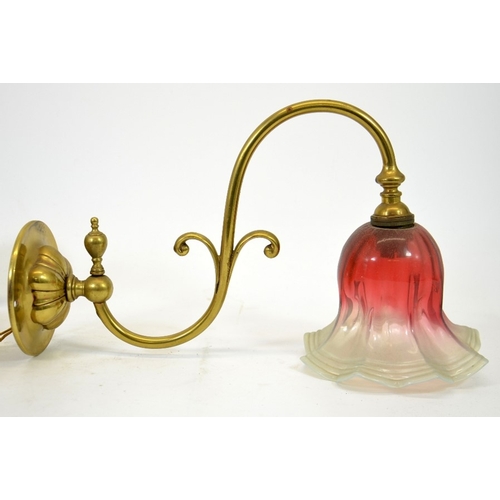 236 - Three Arts and Crafts wall mounted brass lights, with opalescent and cranberry glass shades, the arm... 