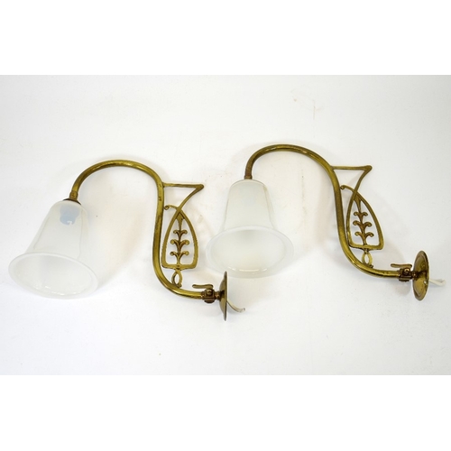 244 - A pair of Art Nouveau brass wall lights, with opaque glass shades, the curved arms with open stylise... 