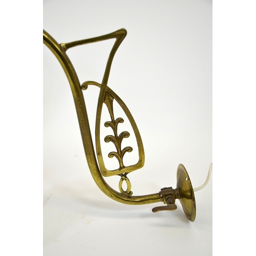 244 - A pair of Art Nouveau brass wall lights, with opaque glass shades, the curved arms with open stylise... 