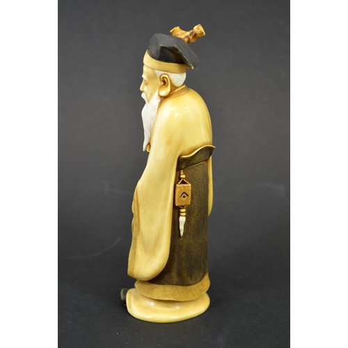 49 - λ A 19th century Japanese carved ivory okimino of an elder, Meiji, modelled holding a staff and fan,... 