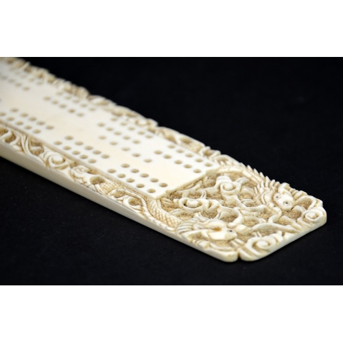 63 - λ A 19th century Chinese carved ivory cribbage board, wedge form, decorated with dragons, 21.5cm lon... 