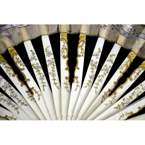 74 - A late 19th/early 20th century fan, the guards and sticks silvered and gilt, the leaf hand painted w... 