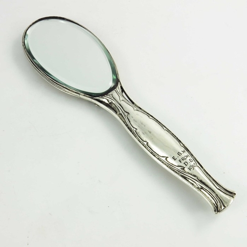 103 - Omar Ramsden and Alwyn Carr, an Arts and Crafts silver hand mirror, London 1915, the oval head embos... 