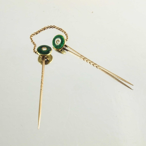 118 - A pair of rose gold stickpins decorated with circular green enamel roundels with diamond centre ston... 