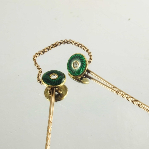 118 - A pair of rose gold stickpins decorated with circular green enamel roundels with diamond centre ston... 