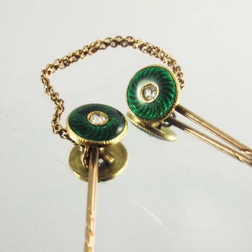 118 - A pair of rose gold stickpins decorated with circular green enamel roundels with diamond centre ston... 