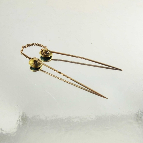 118 - A pair of rose gold stickpins decorated with circular green enamel roundels with diamond centre ston... 