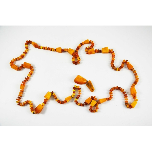 129 - A butterscotch amber necklace, rough cuboid cut, with two further pieces of amber, 178cm long, 149g