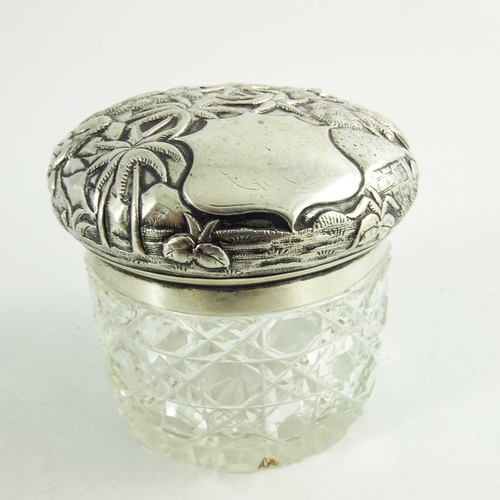 19 - A 19th century Oriental white metal lidded cut glass jar, repousse decorated and etched with village... 