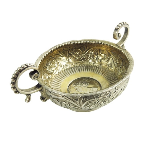 56 - An 18th century two handled white metal bowl, the base set with a Queen Anne silver shilling, 1711, ... 