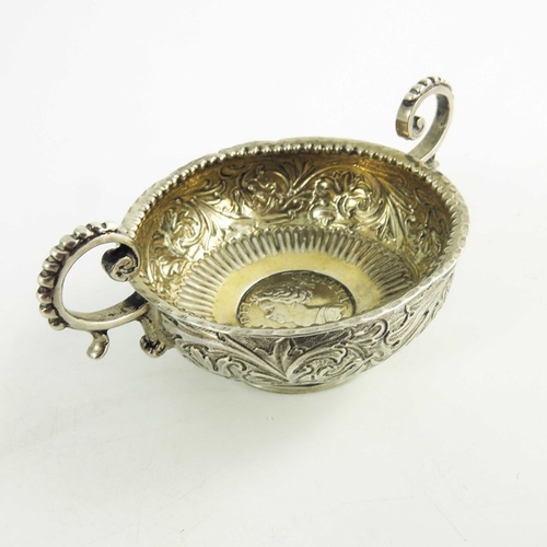 56 - An 18th century two handled white metal bowl, the base set with a Queen Anne silver shilling, 1711, ... 