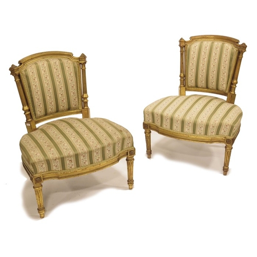 229 - A Pair of Louis XVI style gilt wood upholstered chairs, 19th century, the back flanked by fluted col... 