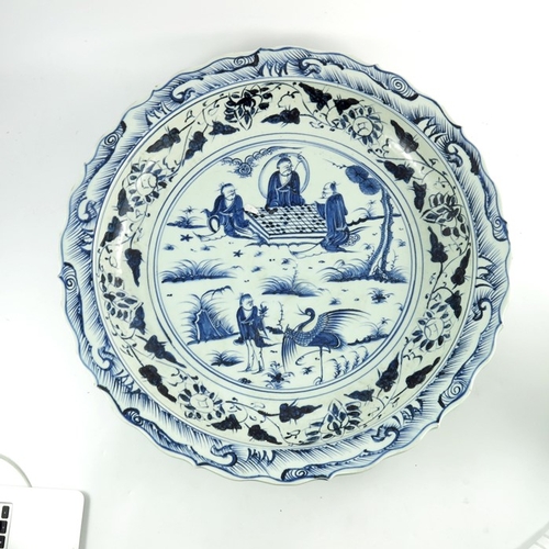 386 - A large Chinese blue and white charger, painted with figures playing a board game in a garden landsc... 