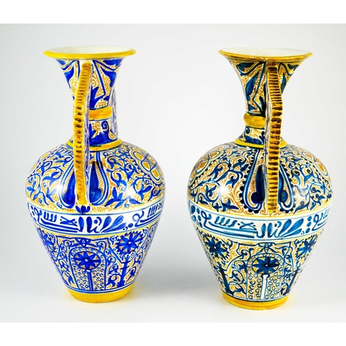 400 - A Near Pair of Middle Eastern Glazed Ceramic two handled ewers, decorated in cobalt blue and ochre c... 