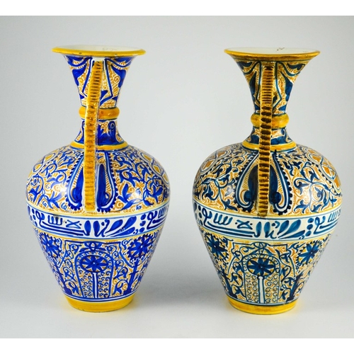 400 - A Near Pair of Middle Eastern Glazed Ceramic two handled ewers, decorated in cobalt blue and ochre c... 