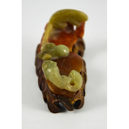 462 - A Chinese carved jade brush rest, modelled as rat and squirrel with fruit on russet leaves, on a car... 