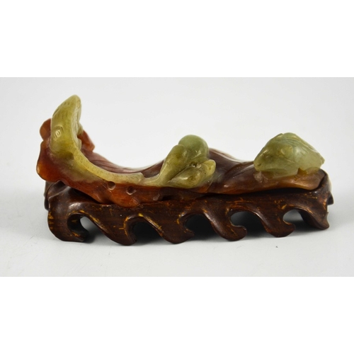 462 - A Chinese carved jade brush rest, modelled as rat and squirrel with fruit on russet leaves, on a car... 