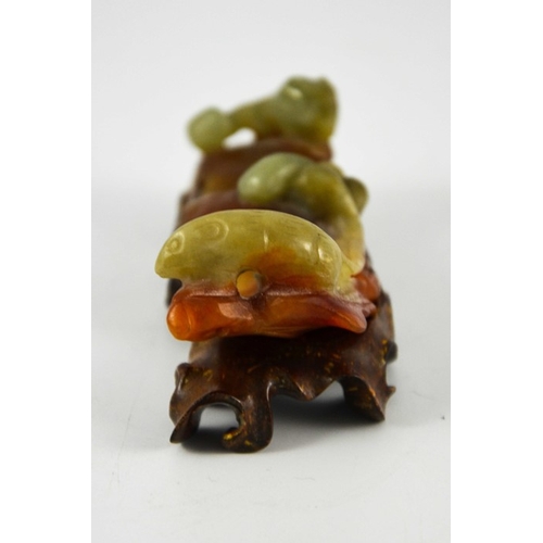 462 - A Chinese carved jade brush rest, modelled as rat and squirrel with fruit on russet leaves, on a car... 